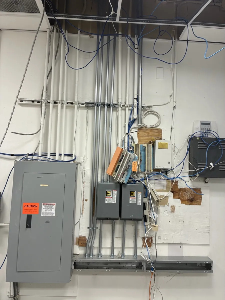 Electrical room with panelboard, disconnects and new conduit runs on the wall