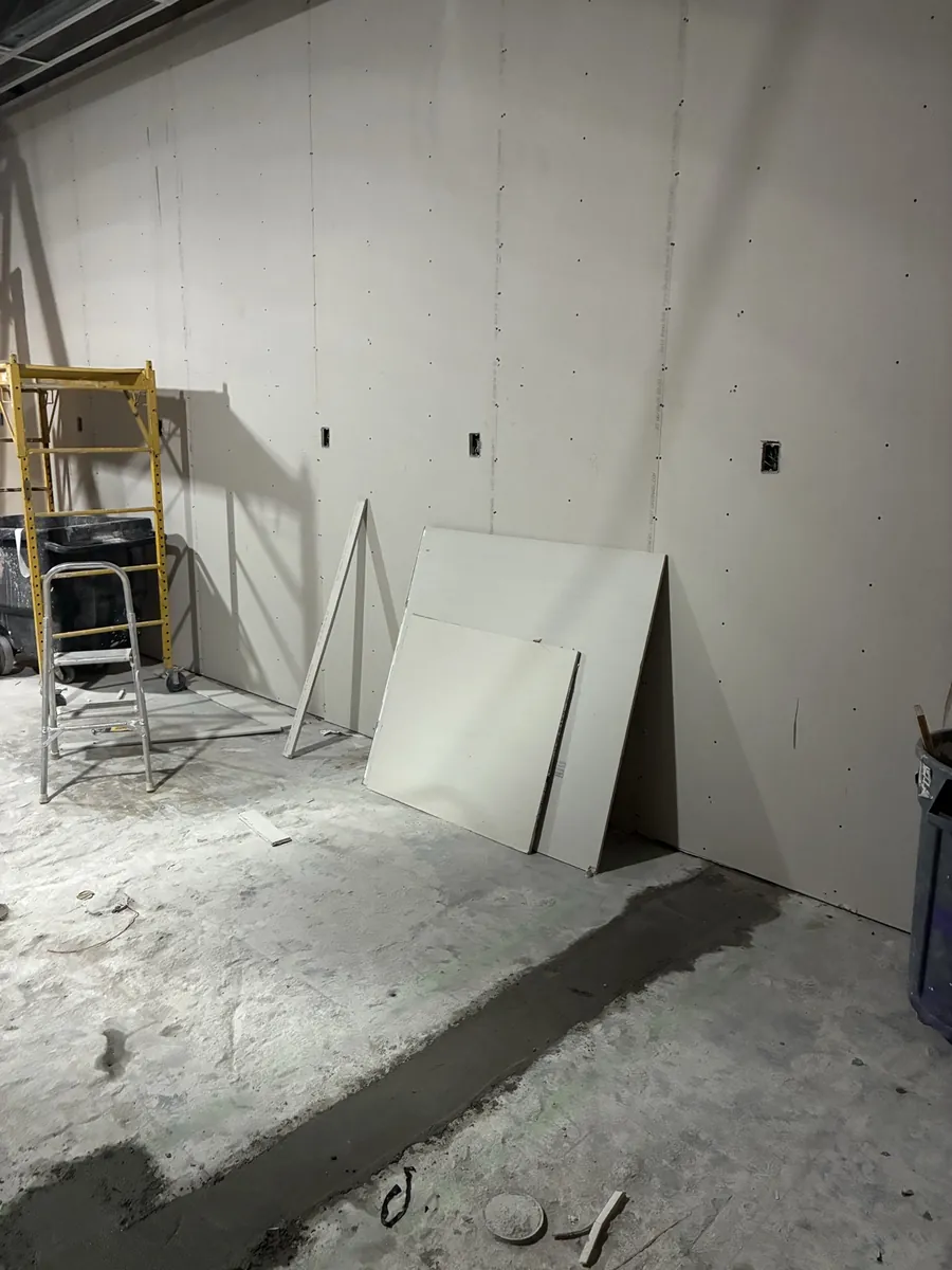 Drywalled retail store wall with device boxes cut in and a patched floor trench