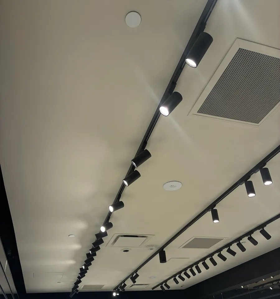 Black track lighting installed along a finished retail store ceiling