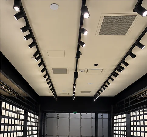 Rows of track lighting along a retail store ceiling, looking toward the storefront